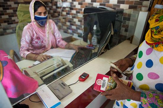 印度西拉那，一名业务经理在帮助一名女性办理银行业务。图片来源：?Gates Archive_Mansi Midha